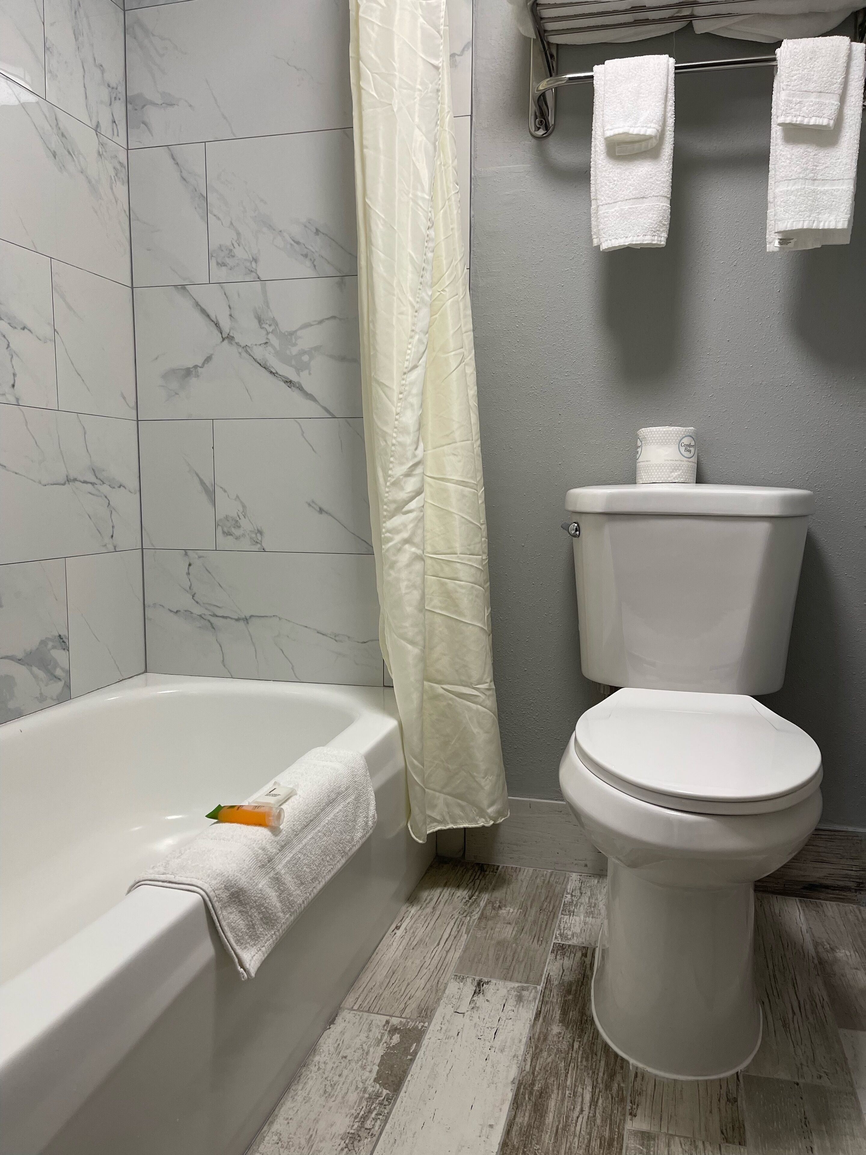 Une salle de bain avec une baignoire, des toilettes et un rideau de douche.