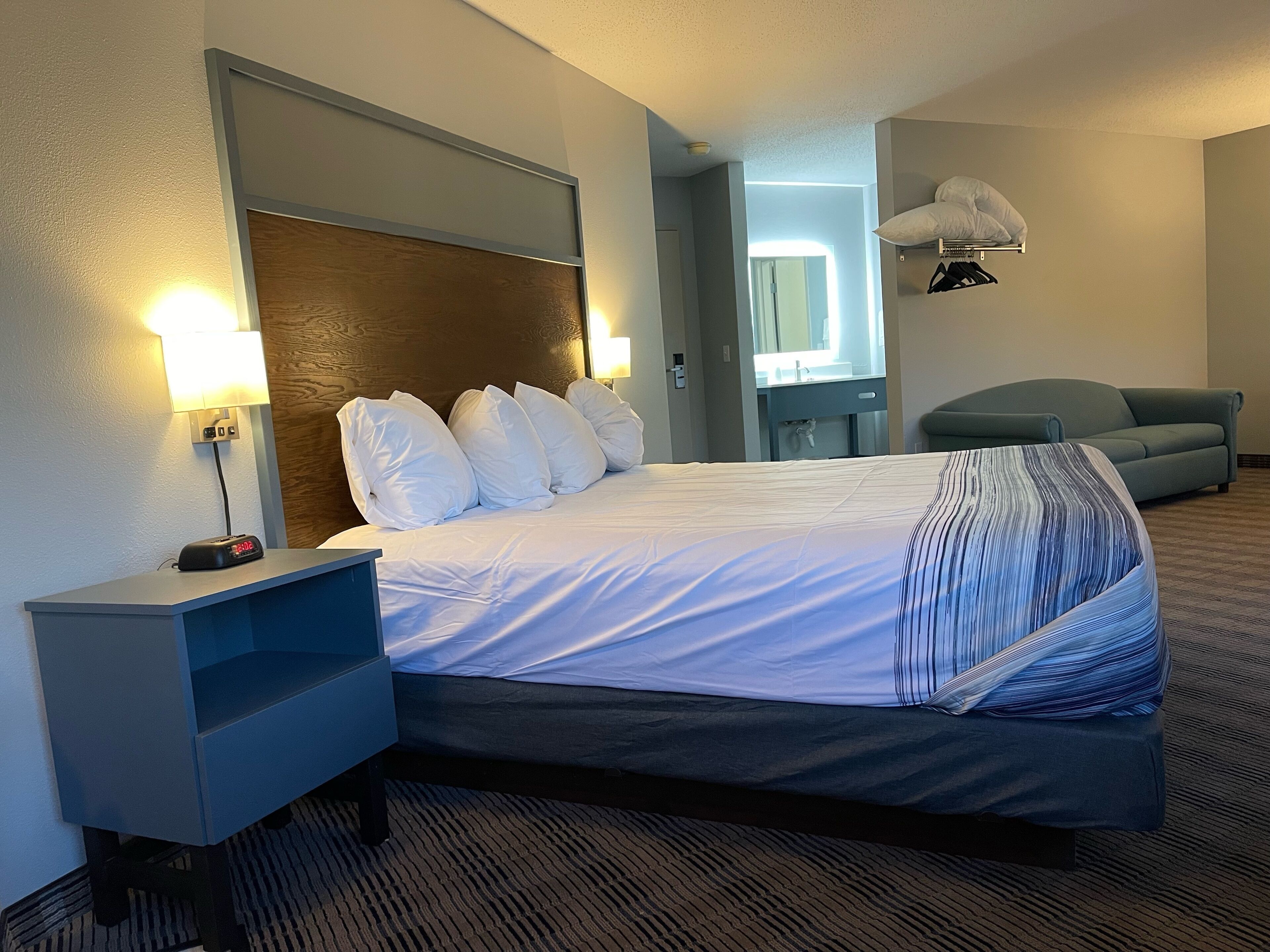 A hotel room with a bed, bedside table, lamp, and a mirror.