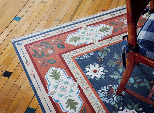 A wooden floor with a patterned rug featuring geometric and floral designs.
