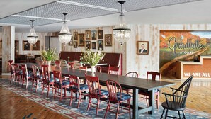 A dining area with a long table, red chairs, and a chandelier. - Graduate by Hilton Storrs (Storrs)