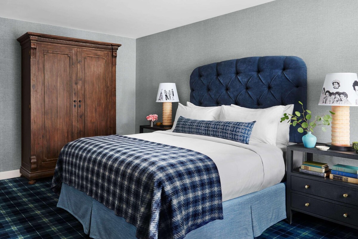 A bedroom with a bed, a nightstand, a dresser, and a lamp.