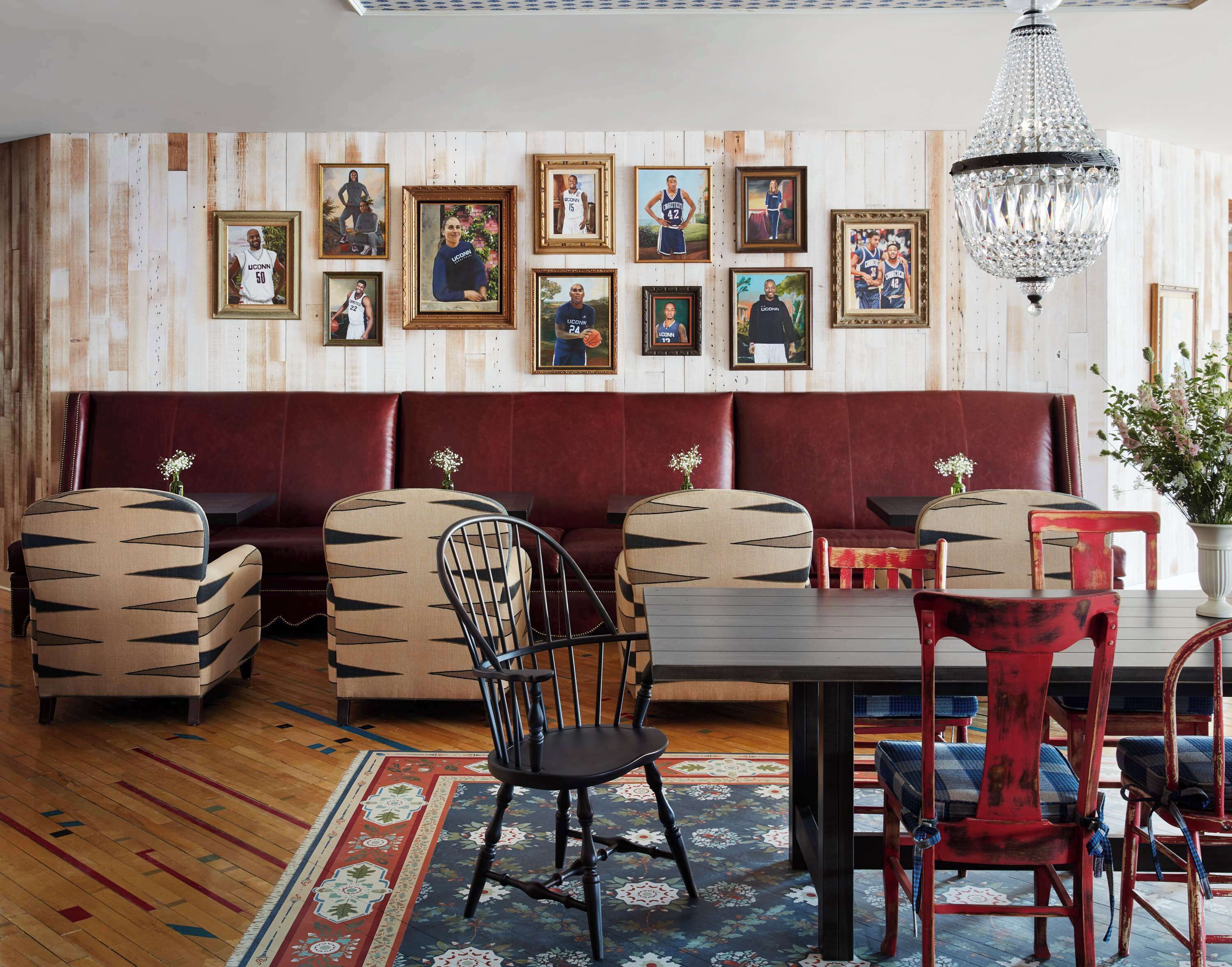 A restaurant with a wooden wall, cushioned seating, framed pictures, and a chandelier.