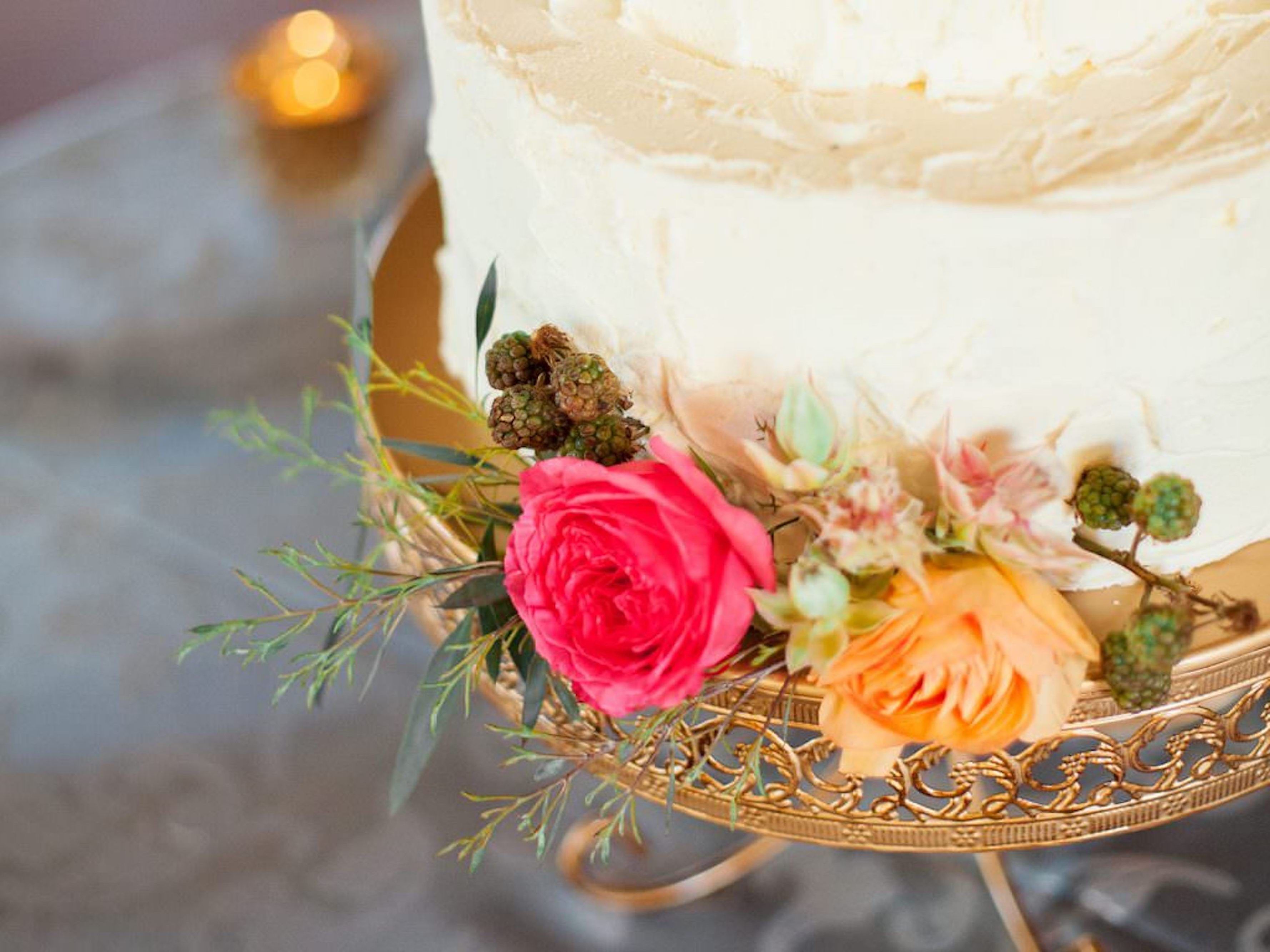 A cake with white frosting and a decorative stand with flowers.