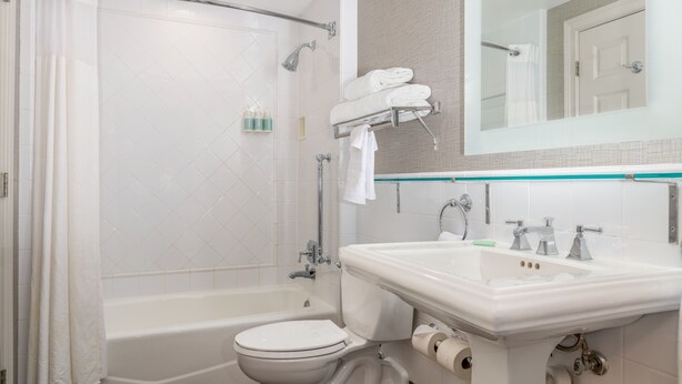 A bathroom with a bathtub, toilet, sink, and a mirror. - Courtyard by Marriott St. Louis Downtown/Convention Center (St. Louis)