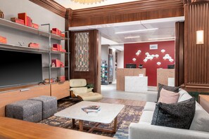A modern lobby with a seating area, a bookshelf, and a reception desk. - Courtyard by Marriott St. Louis Downtown/Convention Center (St. Louis)