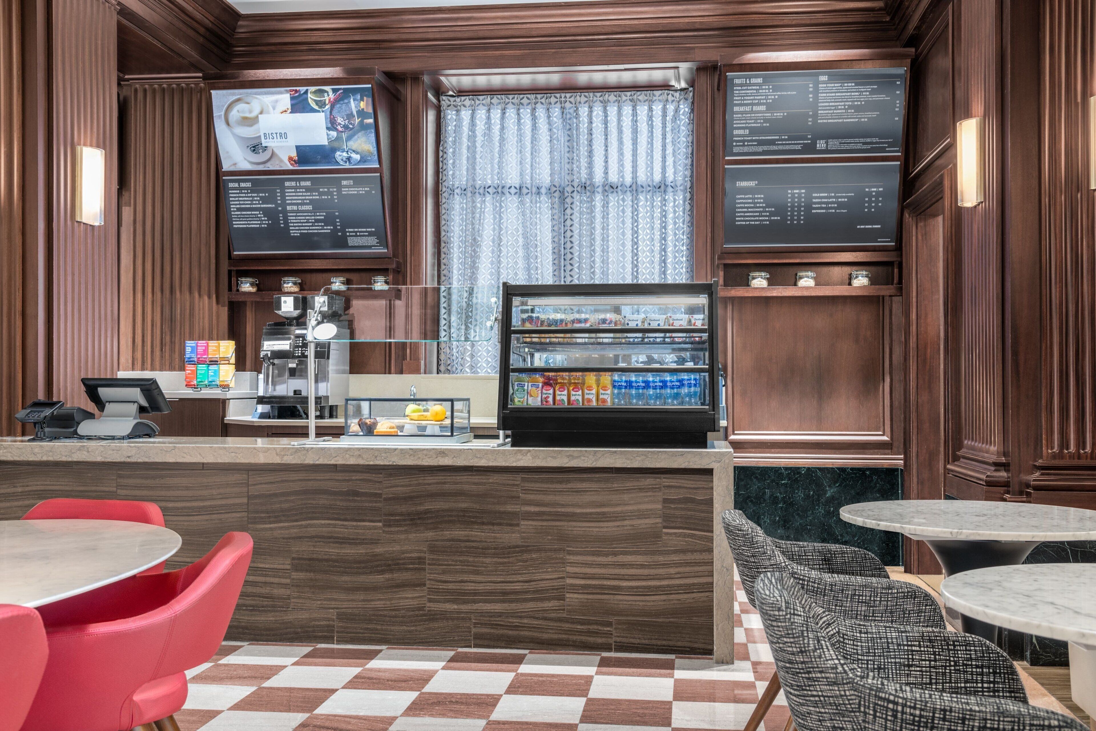 A bistro with a marble counter, red and black upholstered chairs, and a checkered floor.