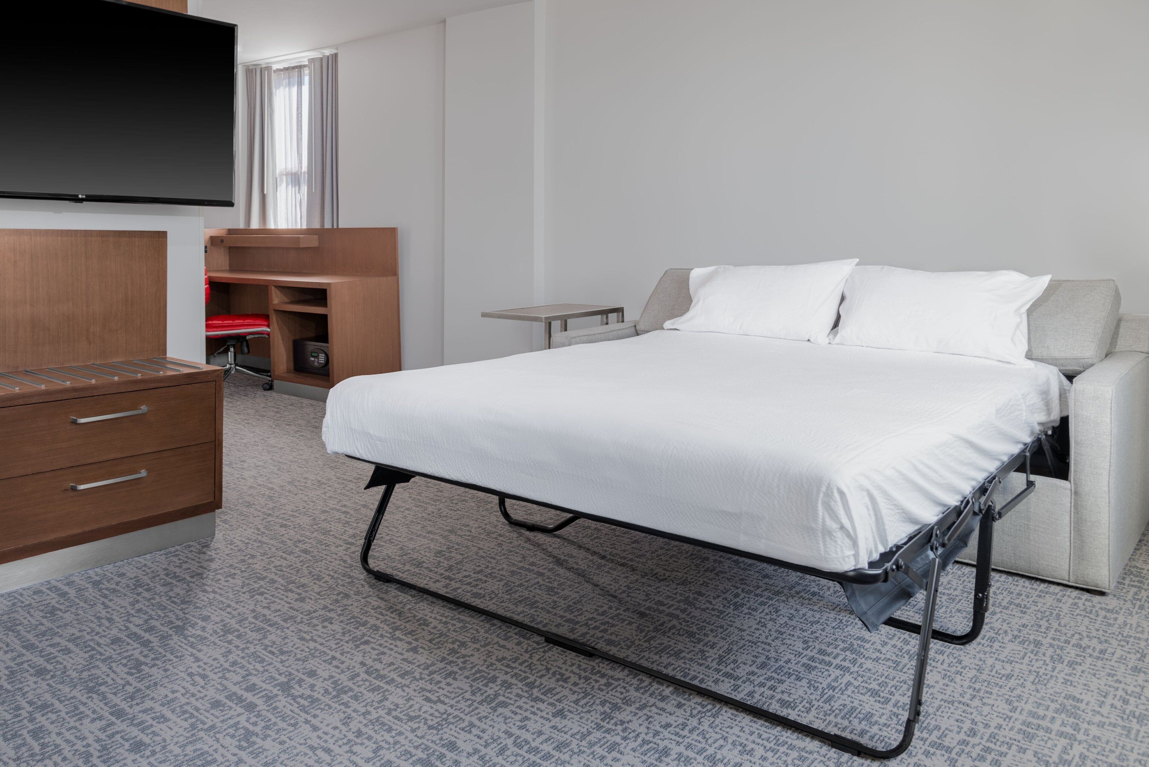 A compact hotel room with a bed, a TV, a desk, and a wardrobe.