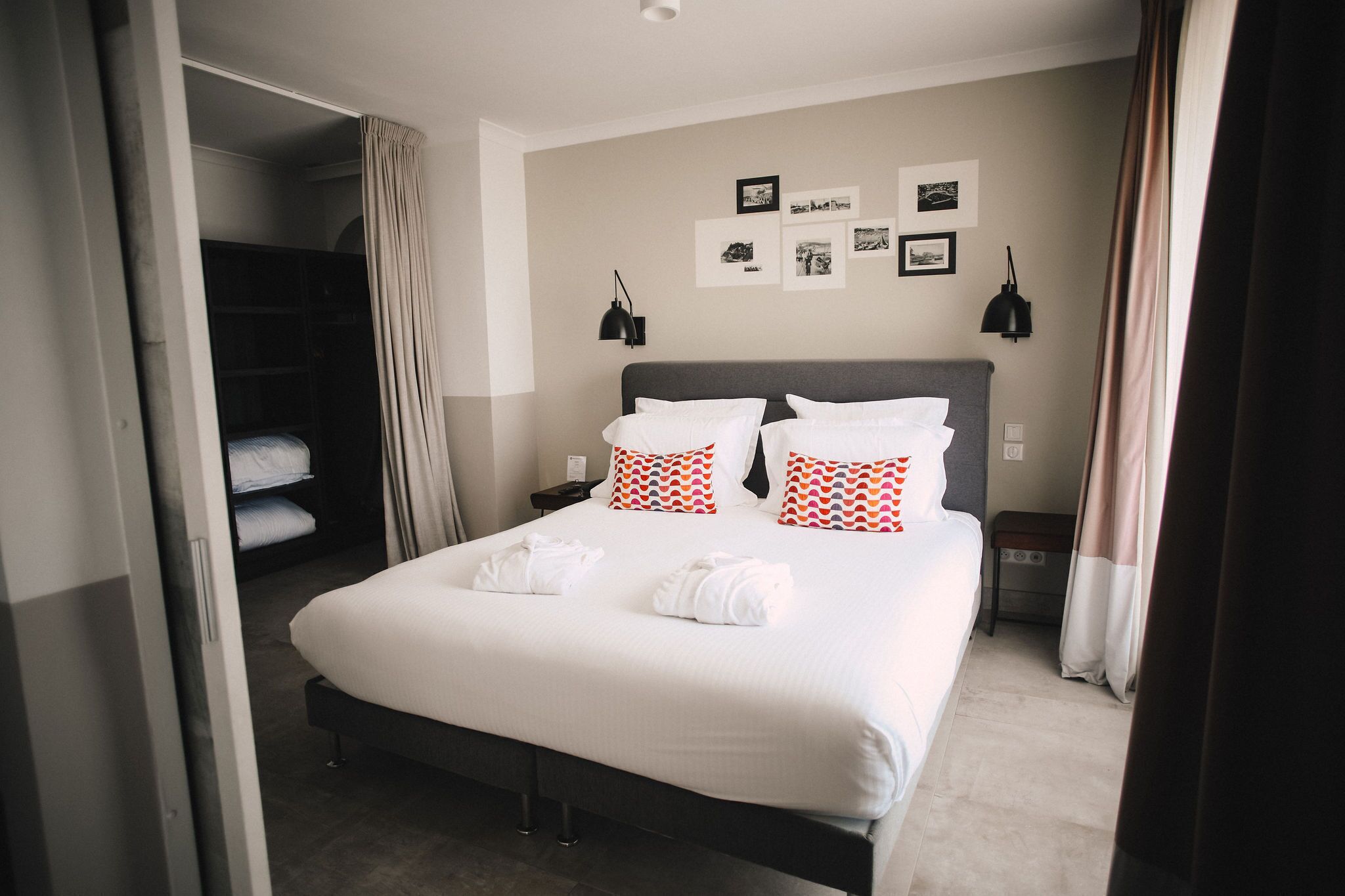Een hotelkamer met een groot bed, een garderobe, een nachtkastje en een wand met ingelijste foto's.