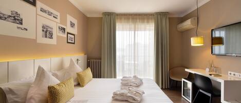 A hotel room with a neatly made bed, a desk with a chair, and a television.