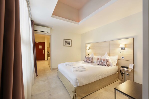 A hotel room with a large bed, bedside tables, a nightstand, and a ceiling light. - Best Western Plus La Corniche (Toulon)