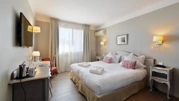 Camera d'albergo con un letto grande, comodini, una scrivania con una lampada e una TV a parete.