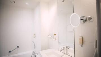 Une salle de bain moderne avec une baignoire, un lavabo et un grand miroir.