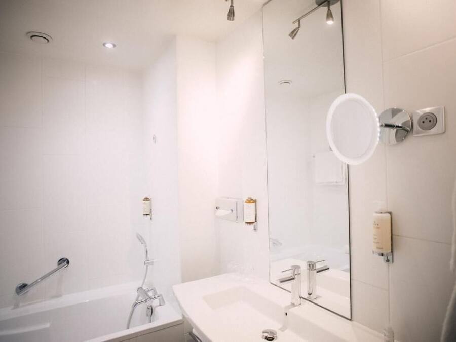 Un bagno moderno con vasca, lavandino e un ampio specchio.