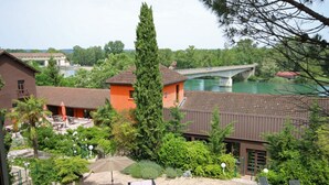 A hotel with outdoor seating, a swimming pool, and a view of a bridge over a river. - Best Western Bridge Hotel Lyon East (Jons)