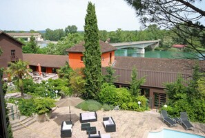 Un hotel con terraza exterior, piscina y vistas a un puente sobre el río.