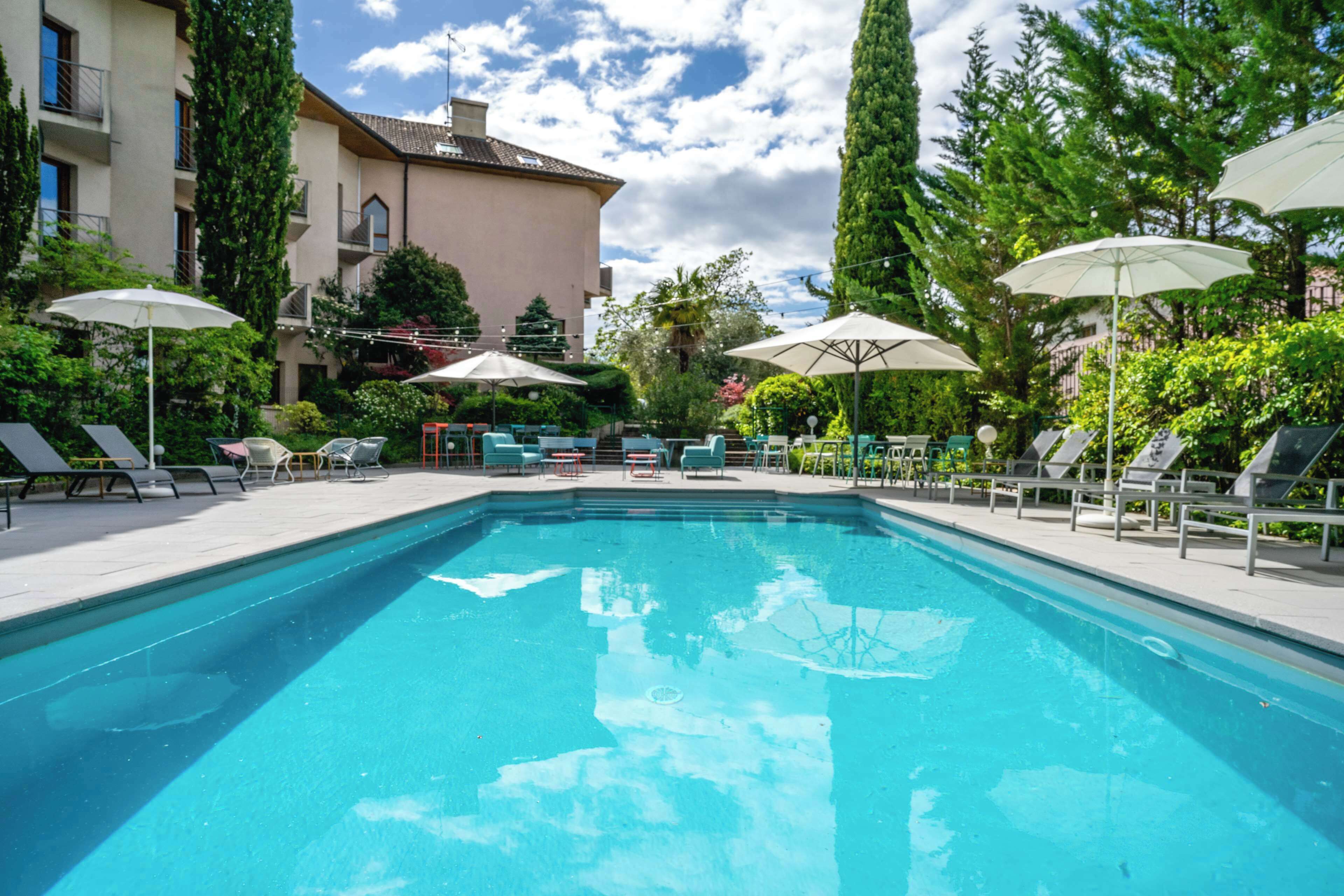 Een buitenzwembad, parasols bij het zwembad en ligstoelen