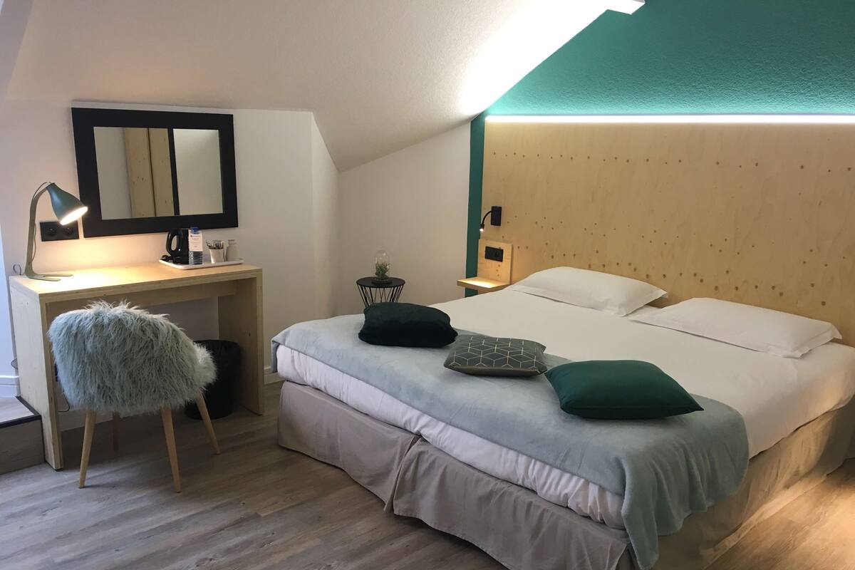 A bedroom with a bed, a desk, a chair, and a nightstand.