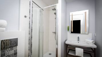 A modern bathroom with a glass-enclosed shower, a white sink, and a mirror above it.
