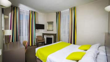 Een hotelkamer met een bed, een bureau, een stoel, een televisie en een open haard.