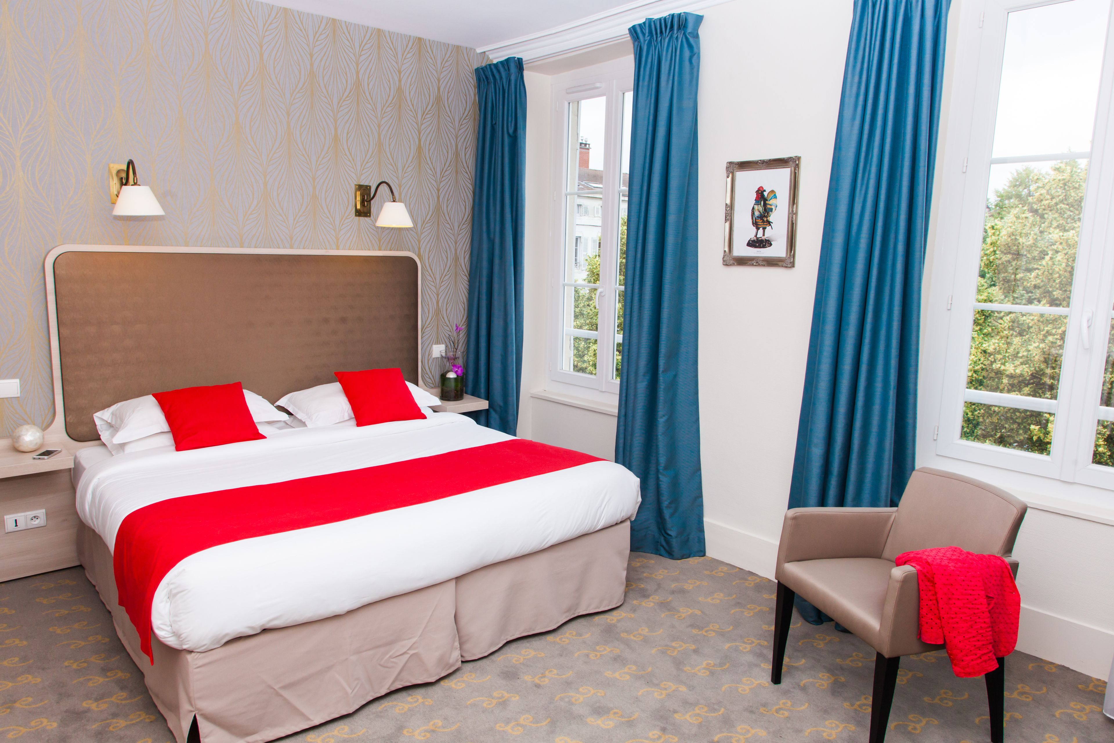 Habitación de hotel ordenada con una cama grande, una silla y un ventanal con cortinas.