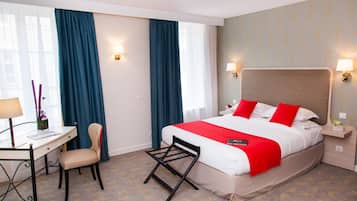 A hotel room with a bed, desk, chair, and two bedside lamps.