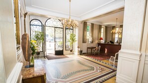 A grand lobby with a large patterned carpet, a chandelier, and a seating area.