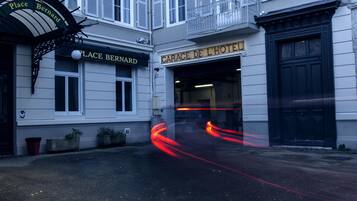 Place Bernard and Garage de l'Hôtel buildings with a classic architectural style, featuring a black entrance door and a sign above the entrance.