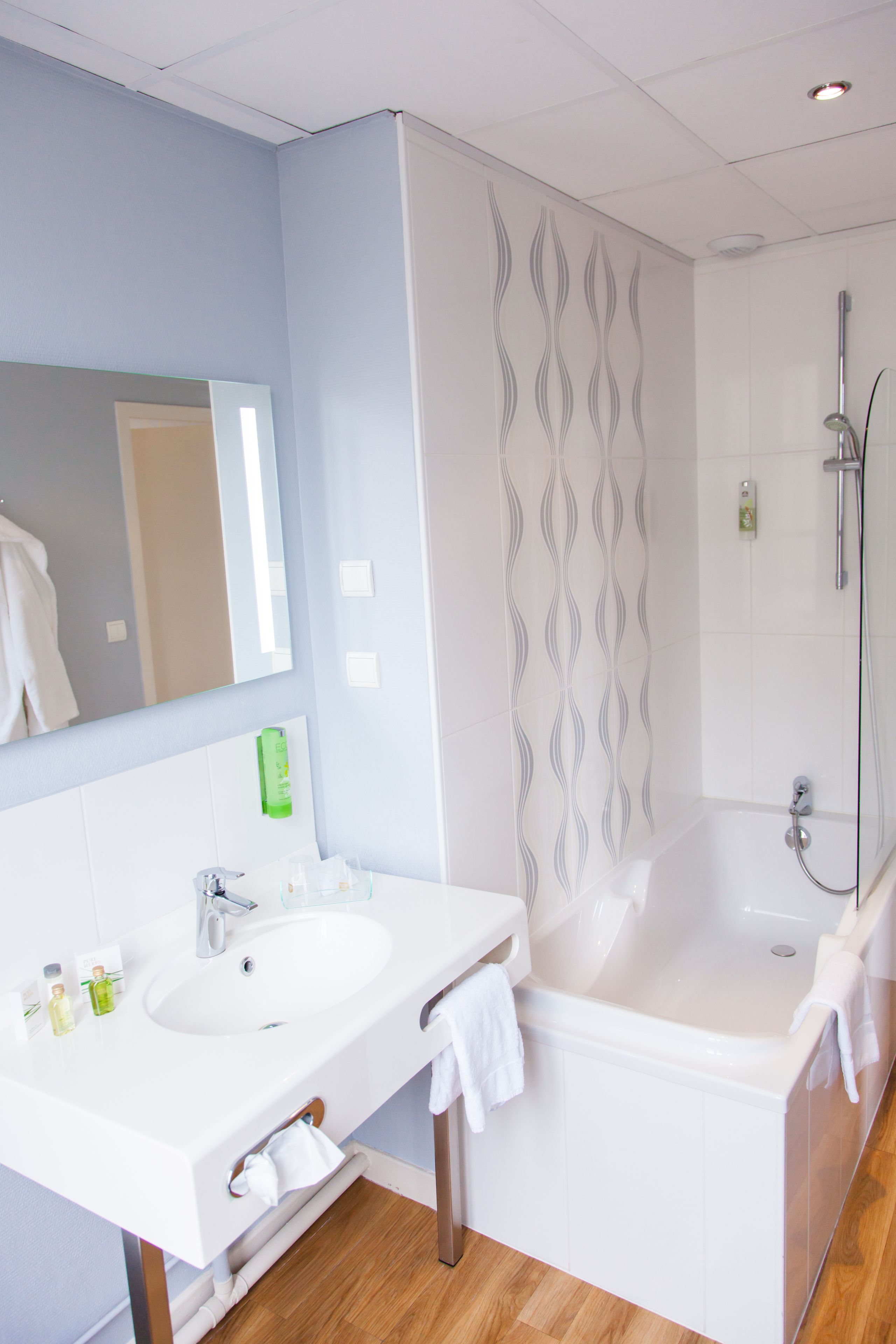 A modern bathroom with two sinks, a large mirror, a shower, and a towel rack.