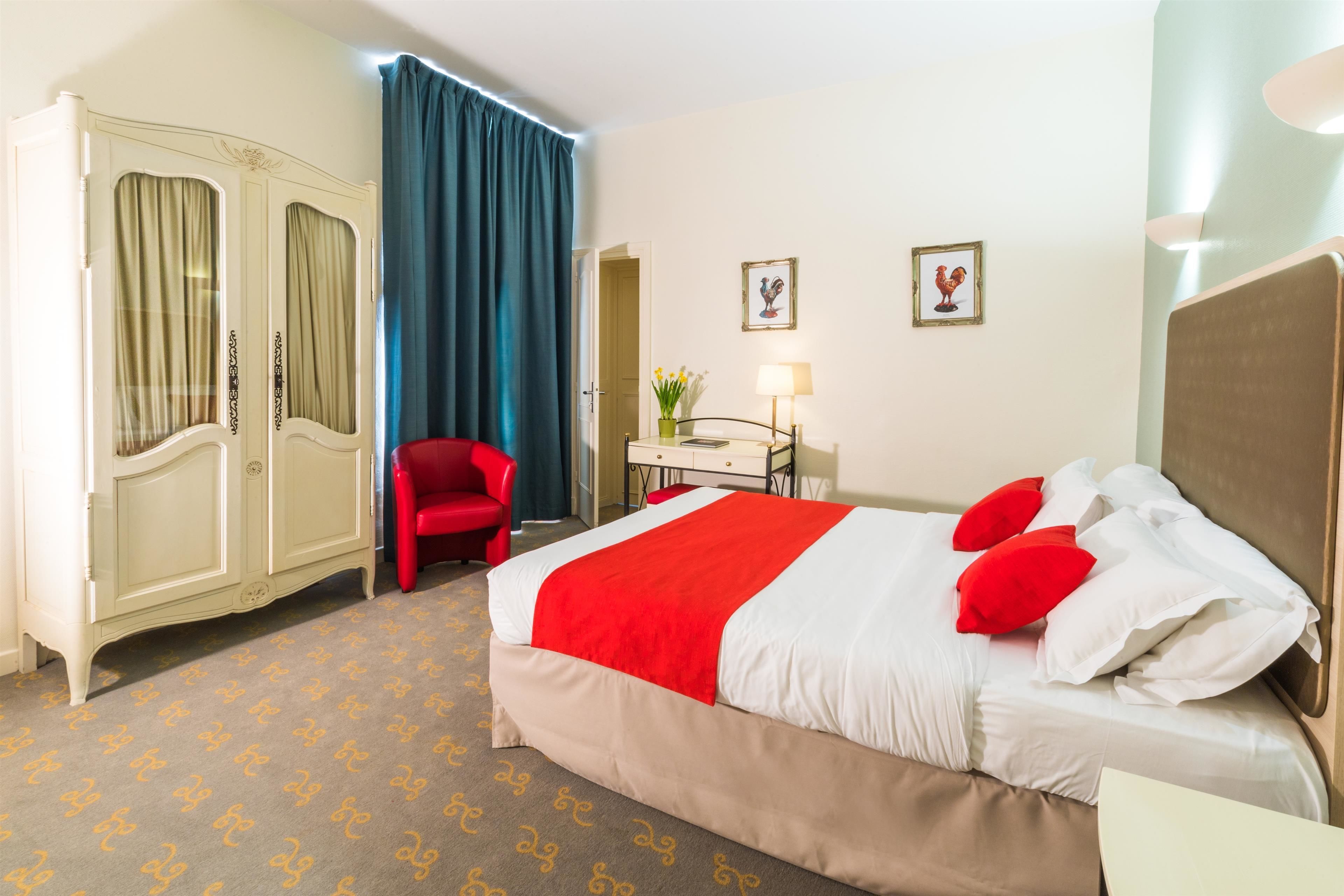 Ein Hotelzimmer mit einem Bett, einem Schreibtisch, einem Stuhl, einem Kleiderschrank und Vorhängen.