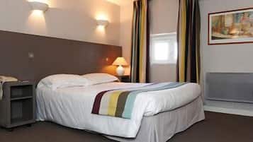 Una habitación de hotel con cama, mesita de noche, lámpara, un cuadro en la pared y ventana con cortinas.