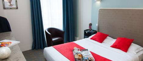 Habitación de hotel con cama, escritorio, silla, bandeja con alimentos para el desayuno y un cuadro en la pared.