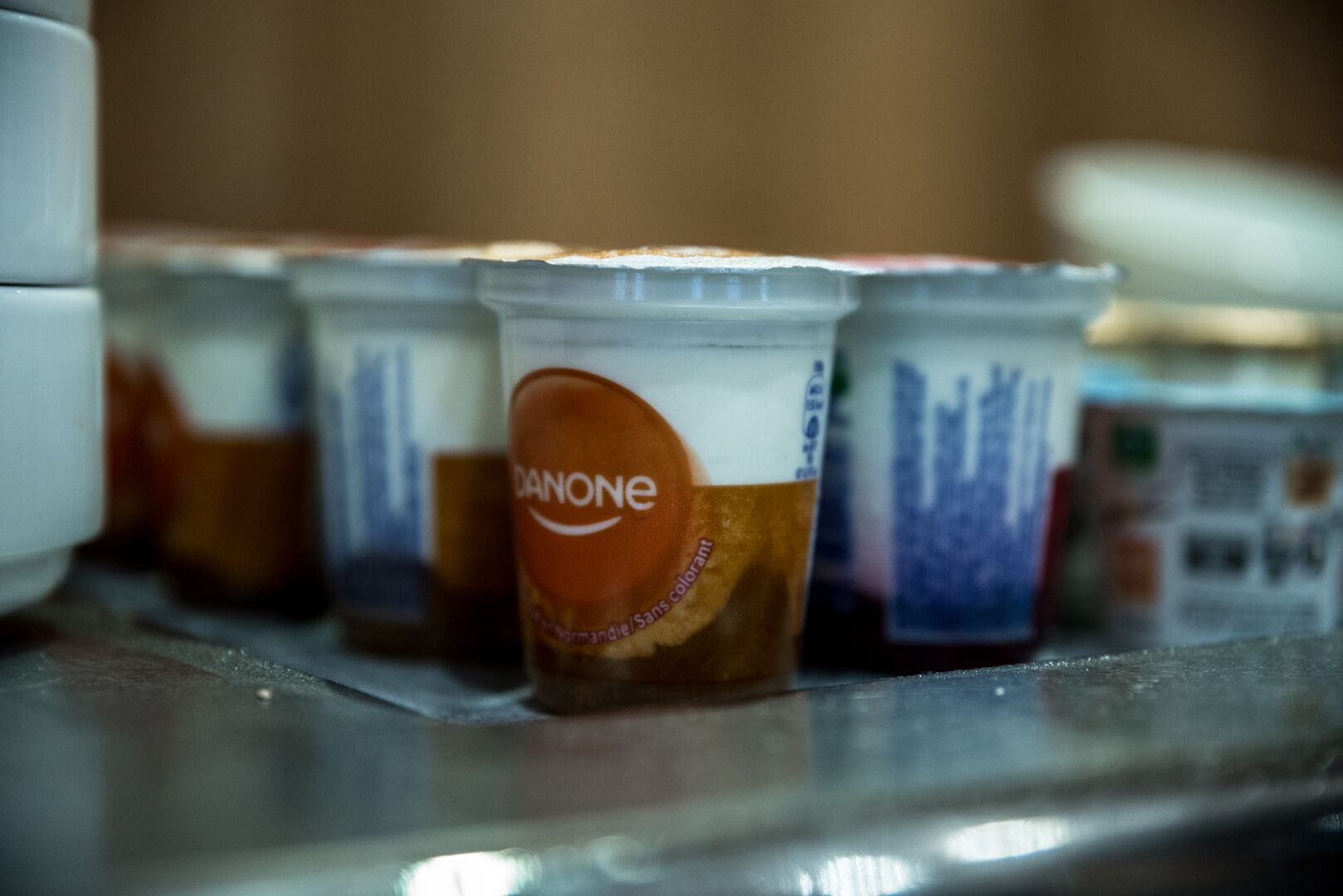 A row of plastic cups with the brand name 'Danone' on them, placed on a metallic surface.