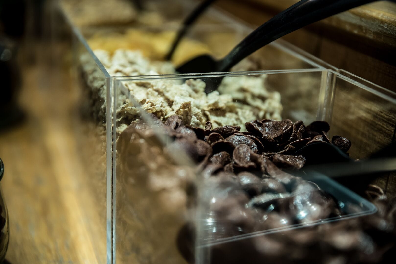 A clear plastic container with various food items, including what appears to be chocolate pieces and possibly some kind of spread or condiment.