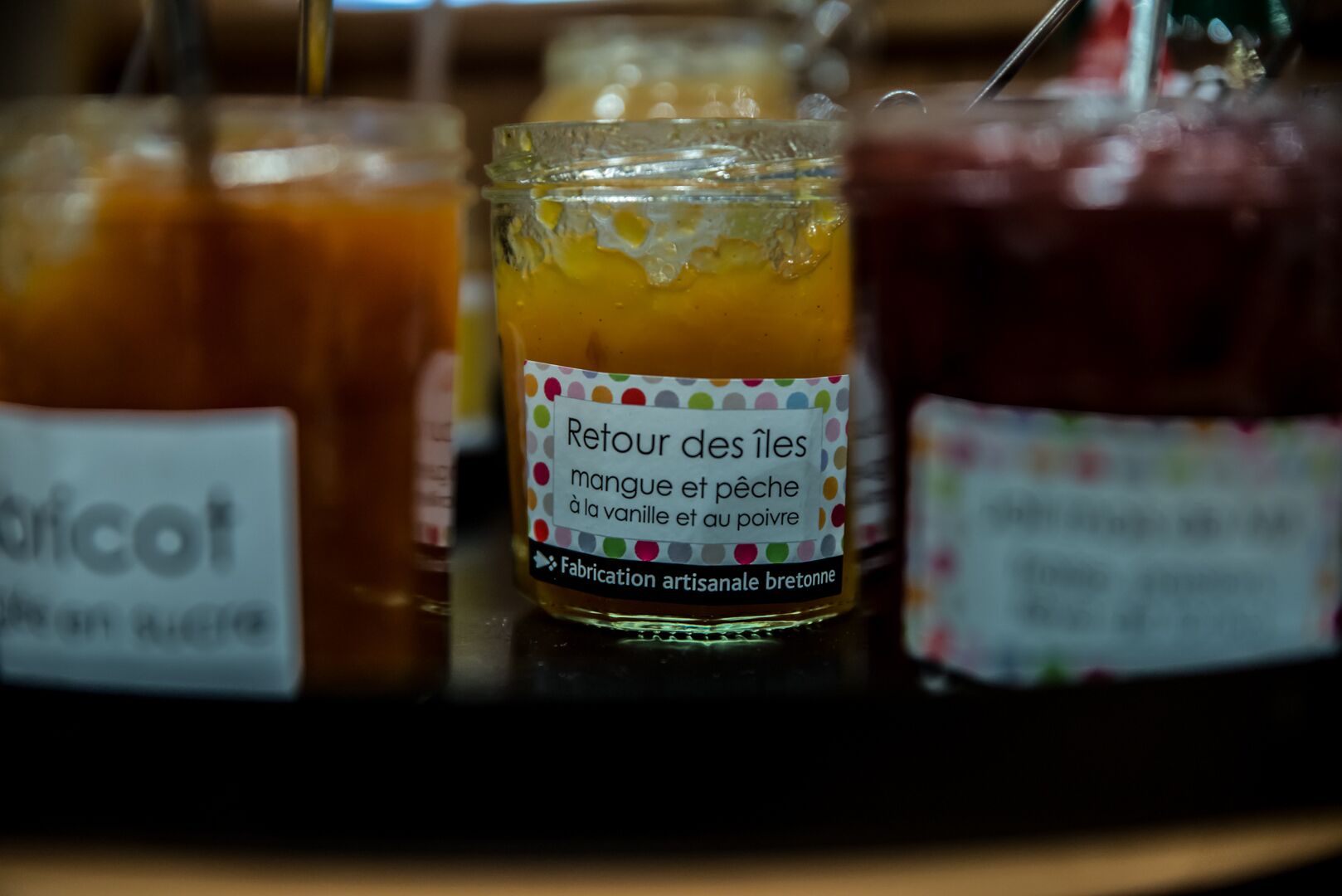 A close-up of three jars with labels, likely containing food items.