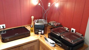 Montaje de bufé con varias estaciones de comida, incluyendo una bandeja de servicio negra con calefacción, una barra de ensaladas y una sección con frascos de condimentos.