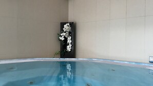 Una piscina con suelo de baldosas y una pared decorativa con flores.