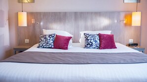 Una habitación de hotel con una cama grande, dos mesitas de noche y dos lámparas de pared.