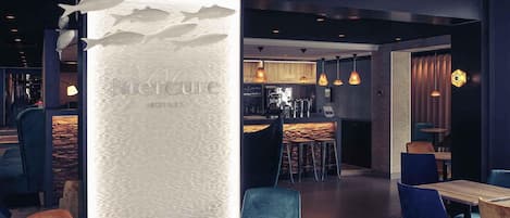 A modern interior with a bar area, seating with blue and wooden chairs, and a decorative wall with fish motifs.