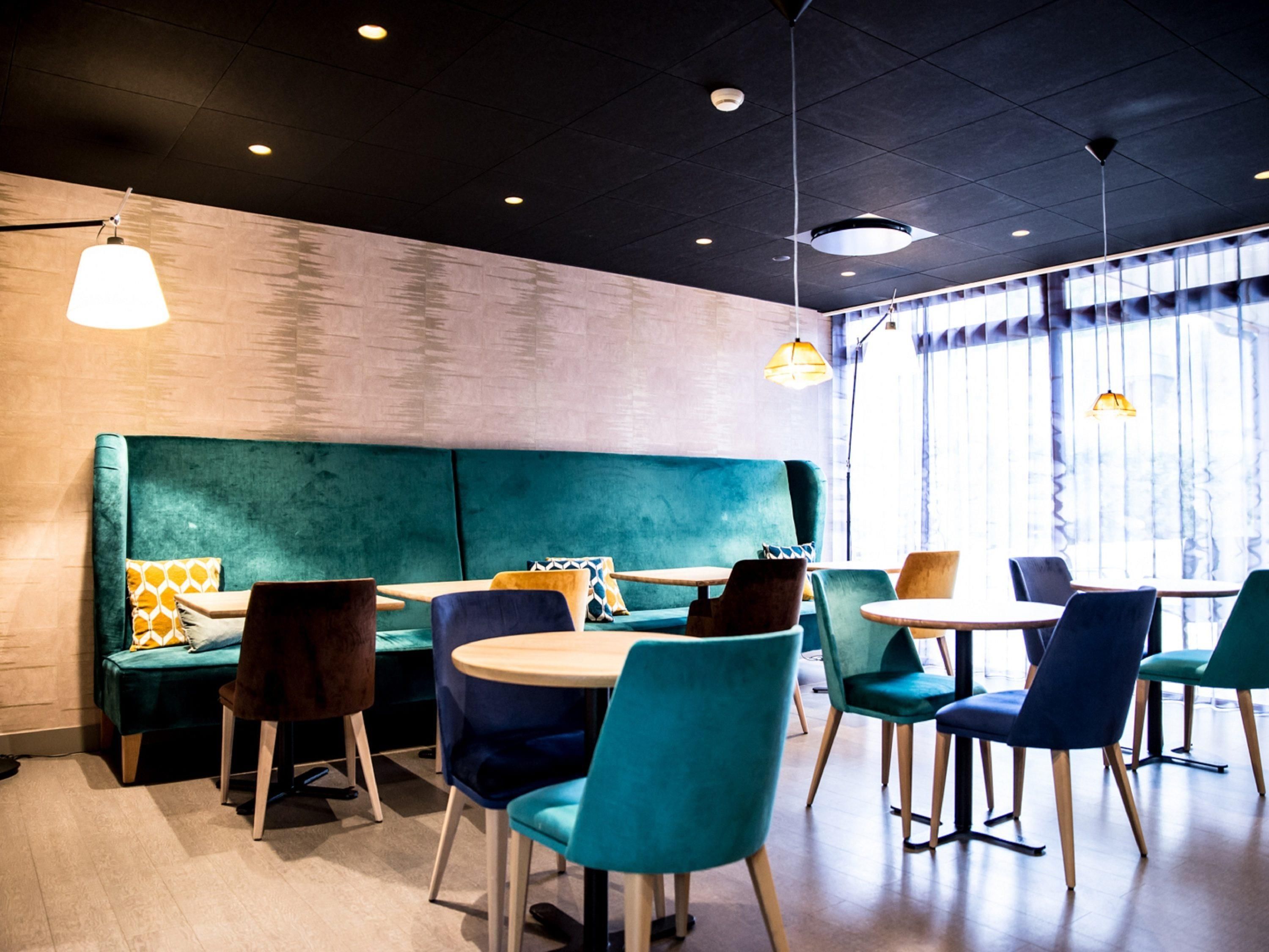 Un interior moderno con asientos color turquesa, mesas de madera e iluminación colgante.