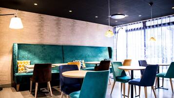A modern interior with teal seating, wooden tables, and pendant lighting.