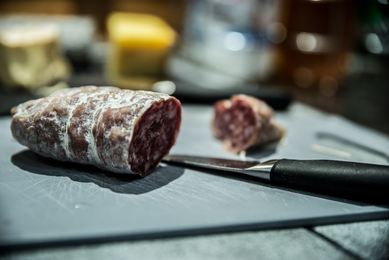 A sliced cured meat on a cutting board with a knife.