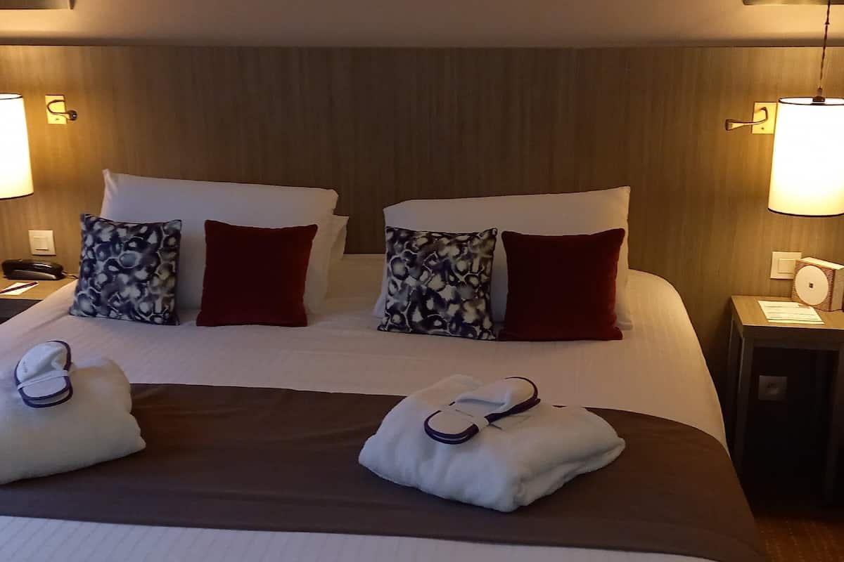 Ein Hotelzimmer mit einem großen Bett, zwei Nachttischen und einem Beistelltisch mit Lampe.