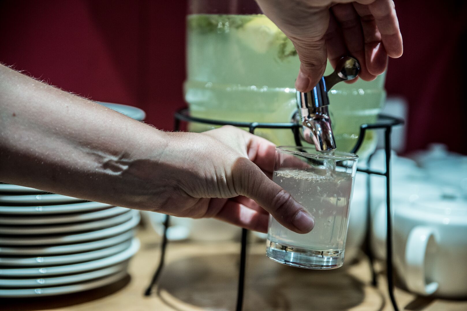 Una mano vertiendo agua en un vaso desde un grifo.