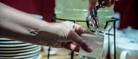 Una mano vertiendo agua en un vaso desde un grifo.