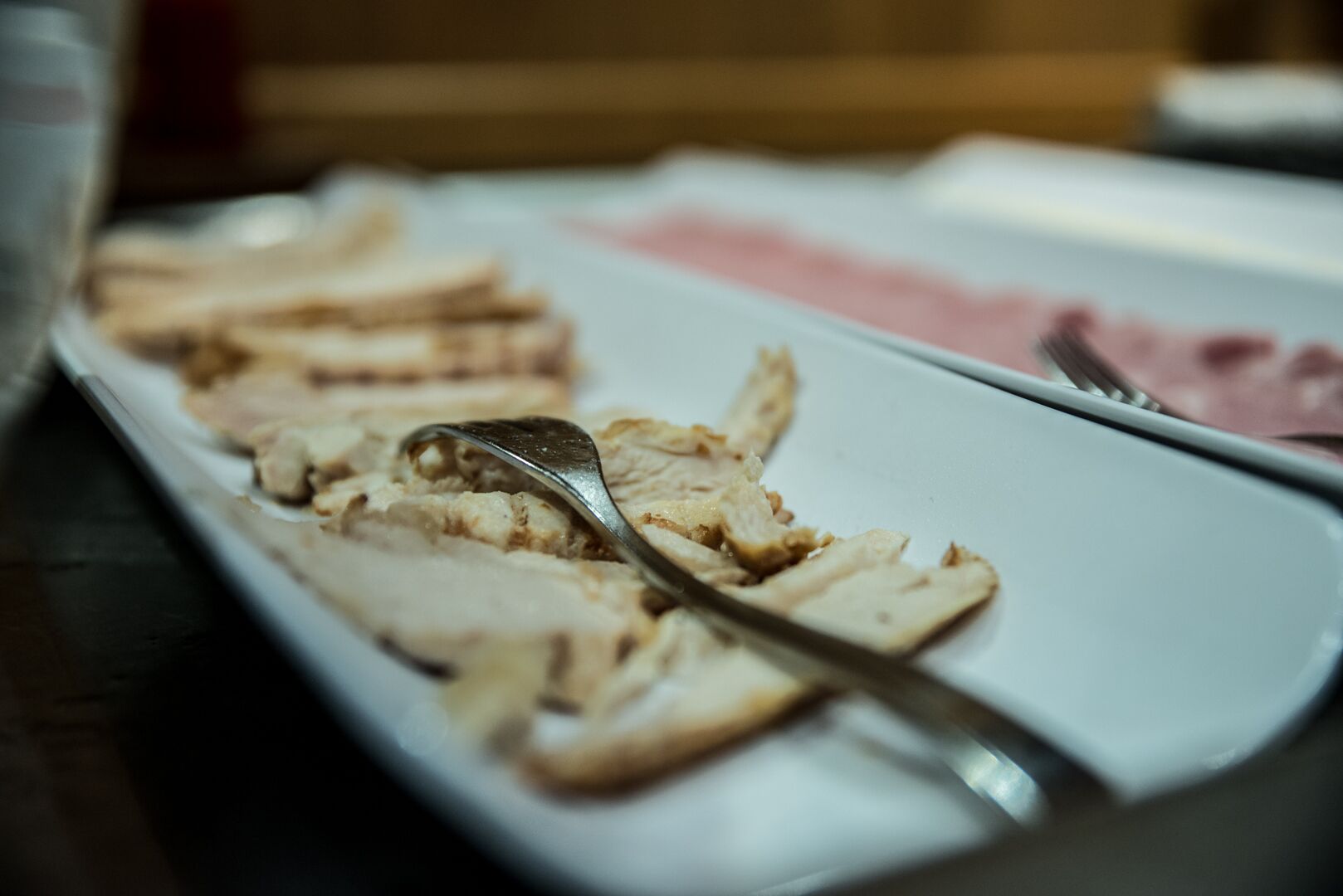 A plate with sliced meat and a spoon.