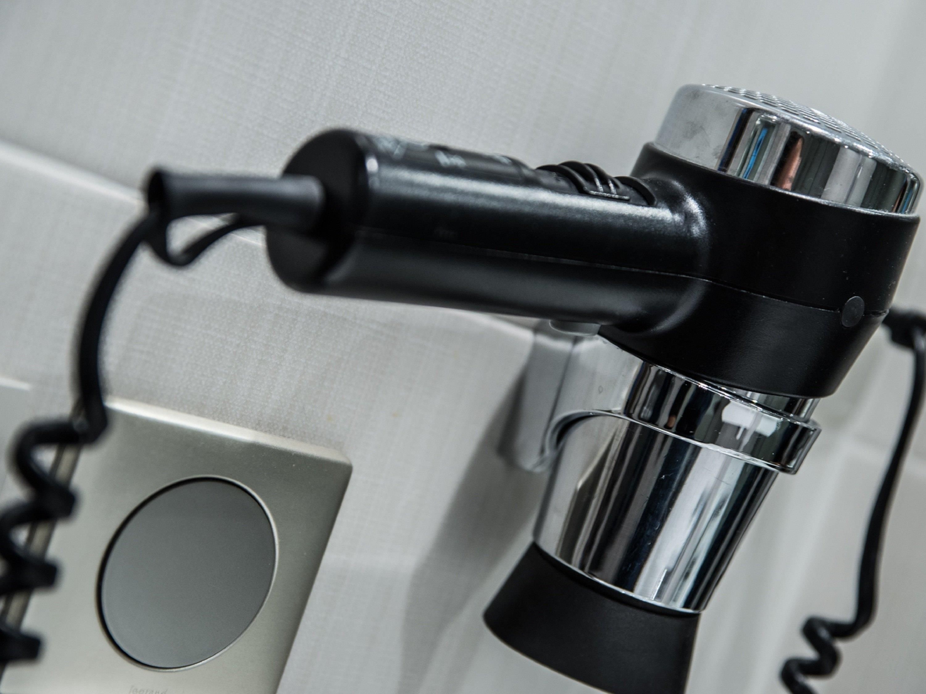 A hair dryer with a cord plugged into a power outlet.