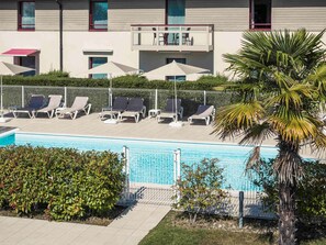 Una piscina al aire libre, sombrillas, tumbonas