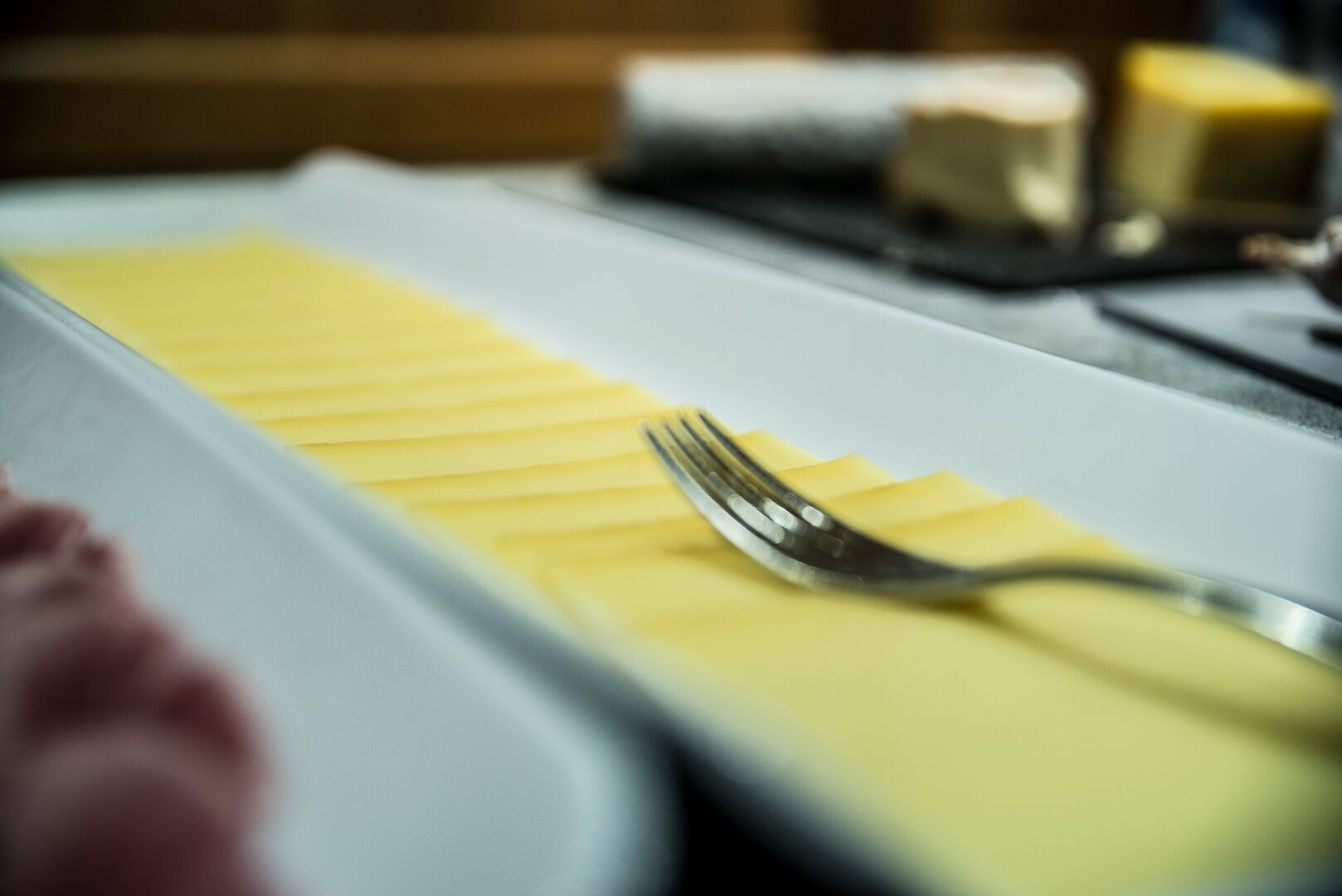 A dining table with a white tablecloth, a fork, and a yellow napkin.