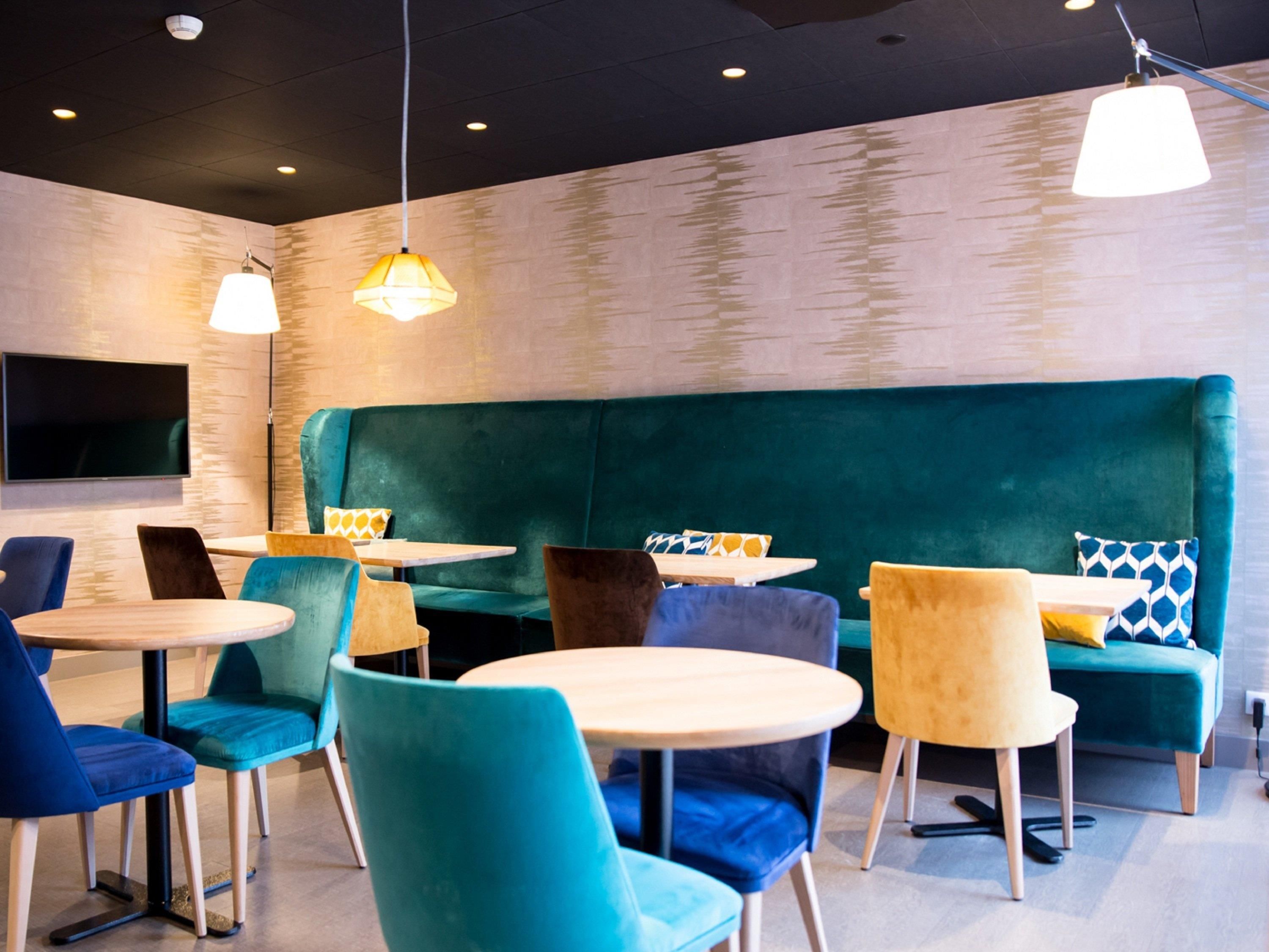 Een modern interieur met blauwgroene zittingen, ronde tafels en hanglampen.