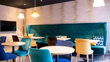 Een modern interieur met blauwgroene zittingen, ronde tafels en hanglampen.